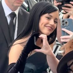 a woman is taking a selfie with her cell phone in front of people wearing suits and ties