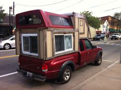 a red pick up truck parked on the side of the road next to a building