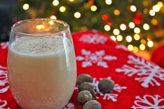 a glass filled with milk sitting on top of a red blanket next to christmas lights