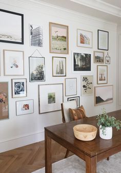 a wooden table sitting in front of a wall filled with pictures and framed art on it