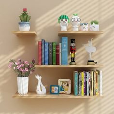 three shelves with books, vases and other decorative items on them against a beige wall