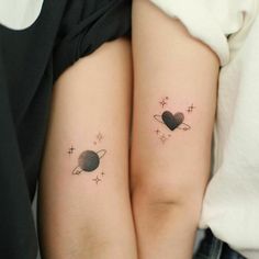 two small tattoos on the arms of girls with saturn and pluto tattoo designs on them