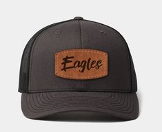 Classic trucker hat style. Custom leather logo. Mid pro profile, Adjustable fit, snap closure back. Cotton-Polyester-Nylon blend. Exceptional quality. Additional Colors: Black & Loden, Black, Beige & Charcoal & Amber, Charcoal & Black, Charcoal & White, Colombia Blue, Heather Gray & White, Khaki & Coffee, Khaki & White, Loden, Navy, Navy & White, Orange, Quarry, White, Alternate White & Black, White, Colombia Blue & Yellow.  Additional Leather Patch Colors: Natural, Brown, Tan, Olive, Gray, Oran Brown Sports Trucker Hat With Curved Bill, Brown Trucker Hat With Curved Bill For Sports, Brown Trucker Hat For Sports, Brown Trucker Hat With Curved Brim For Sports, Outdoor Brown Baseball Cap With Letter Patch, Brown Snapback Hat For Sports With Curved Bill, Brown Trucker Hat With Letter Patch For Outdoor, Brown Snapback Hat With Letter Patch For Outdoor, Adjustable Brown Trucker Hat For Sports