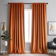 an orange curtain hanging in front of a window with a chair and potted plant