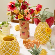 a table topped with vases filled with different types of flowers and fruit on top of it