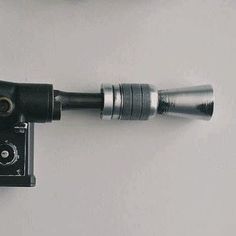 an old camera attached to a wall with a metal tube on it's side