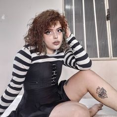 a woman sitting on top of a bed wearing a black and white dress