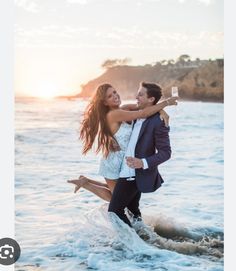 a man in a suit and tie is holding a woman on his back as they walk through the water