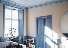 a living room filled with furniture and a large round mirror on the wall next to a window