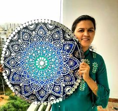 a woman holding an intricately designed plate in front of a cityscape background