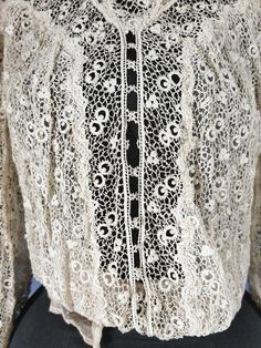 an antique lace blouse with black and white details on the collar, long sleeves and cuffs