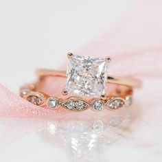 an engagement ring with a princess cut diamond in the center and side stones on each band