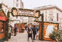 people are walking through an outdoor market with christmas decorations