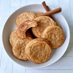 cinnamon sugar cookies in a white bowl with cinnamon sticks sticking out of the top one