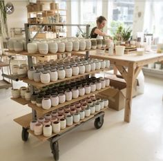 a woman working in a pottery shop with lots of pots and jars on the shelves