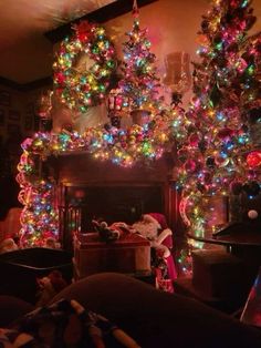 a living room filled with lots of christmas lights next to a fire place covered in santa claus