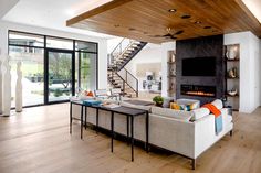 a living room with white couches and a fireplace in the center, surrounded by glass doors