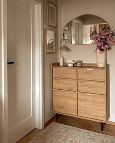 a wooden dresser sitting in front of a mirror on top of a hard wood floor