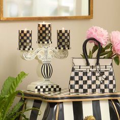 a black and white table topped with vases filled with flowers next to a mirror