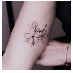 a woman's arm with a small flower tattoo on the left side of her arm