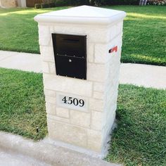 a mailbox sitting on the side of a sidewalk in front of a house with grass