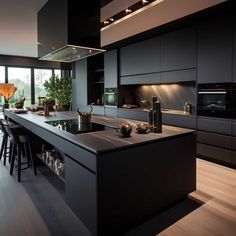 a modern kitchen with black cabinets and counter tops, along with bar stools in the center