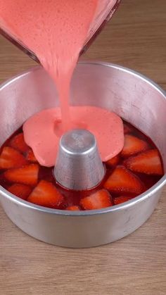 strawberries being poured into a saucepan on a wooden table