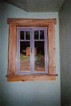 an open window in the corner of a room with a wooden frame and wood trim