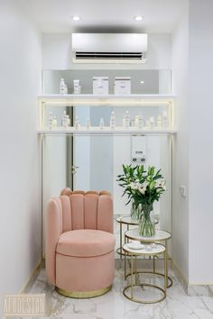 a living room with a pink chair and round table in front of a white wall