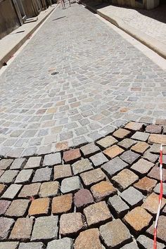 a red fire hydrant sitting on the side of a brick road next to a building