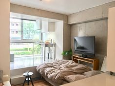 a bedroom with a bed, tv and table next to a window in the room