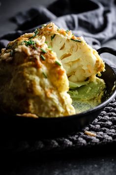 a close up of food in a skillet on a table with a towel and cloth