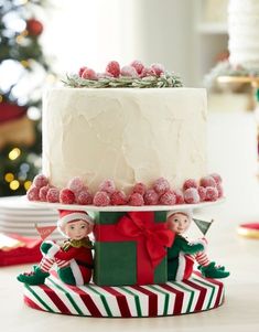 a christmas cake decorated with candy and elf figurines sitting on top of it