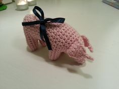 a pink crocheted pig with a black ribbon tied around its neck