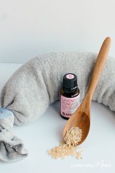 a wooden spoon sitting on top of a pillow next to a bottle of essential oils