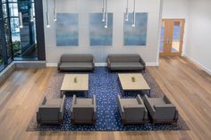 an office lobby with couches, tables and chairs in front of large glass windows