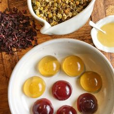 an assortment of candies in a white bowl on a wooden table next to other condiments