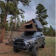 an suv parked in the woods with its roof tent on it's back end