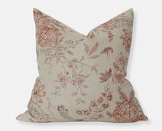 a pillow with an orange and pink floral pattern on it, sitting on a white surface