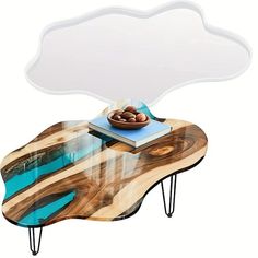 a wooden table with a glass top and metal legs, topped with an acrylic cloud