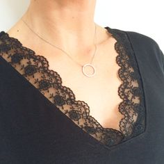 a woman wearing a necklace with a circular pendant on it's neck and black lace