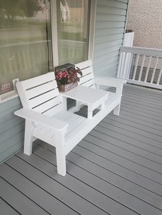 a white bench sitting on top of a wooden porch