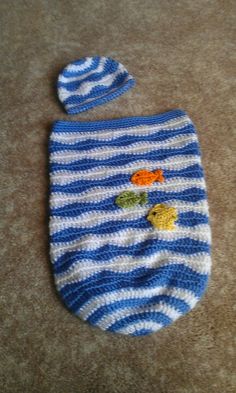 a blue and white striped knitted baby bib with fish applique on it