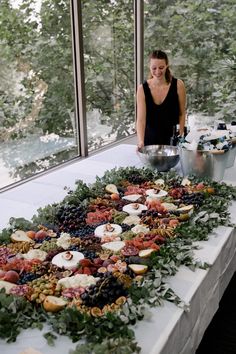 a woman standing in front of a table filled with fruits and vegetables on top of it