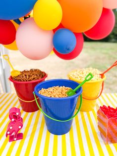 colorful balloons and buckets filled with cereal on a table