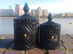 two black canisters sitting next to each other on a brick walkway near the water