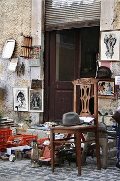 an old chair and table in front of a building with pictures on the wall behind it