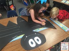 three children sitting at a table with paper cutouts on it