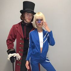 a man and woman dressed in costumes posing for the camera with one holding his hand up