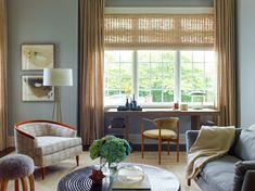 a living room filled with furniture and a window covered in shades of brown, white and blue